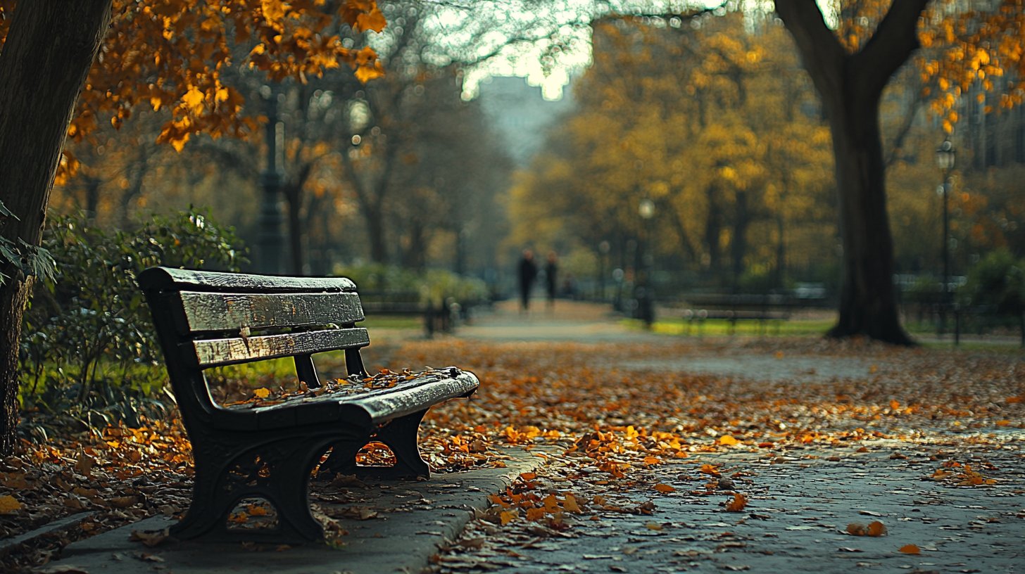 Eine leere Parkbank im Herbst mit fallenden Blättern, symbolisiert emotionale Unverfügbarkeit und Einsamkeit.